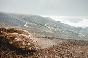 Top of crater Mount Etna volcano, frozen cold lava smokes, thick clouds