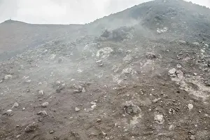 Earthquake Prints: Top of crater Mount Etna volcano, frozen cold lava smokes, thick clouds