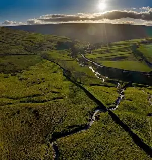 Dales Prints: Cray Gill alongside Buckden Pike looking into the setting sun aerial view from drone