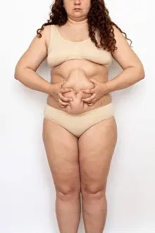 Unrecognizable Prints: Cropped photo of overweight woman with long curly hair wearing beige underwear