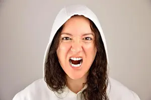 Anger Prints: Cropped portrait of a young woman showing the teeth and shouting passionately isolated on a gray background