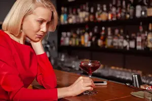 Exhausted Prints: Cropped shot of a sad woman drinking at the bar