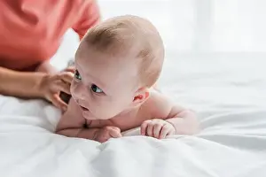 Bedding Prints: cropped view of woman doing massage to baby lying on bed at home