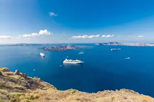 Cruise ship near Santorini, summer travel tourism boats in blue sea bay, cliffs of Santorini volcano island. Famous travel destination