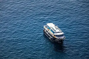 Cruise ship near Santorini, summer travel tourism boats in blue sea bay, cliffs of Santorini volcano island. Famous travel destination