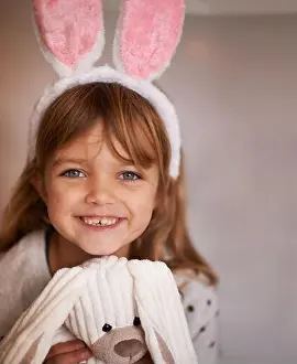 Playtime Prints: Cuddly companion. Portrait of an adorable little girl wearing bunny ears and holding her toy rabbit