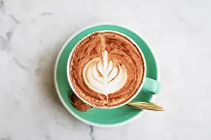 Caffeine Prints: A cup of coffee with latte art on top on light background, closeup top view