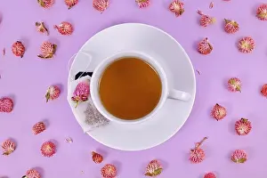 Teacup Prints: Cup of tea surrounded by dried globe amaranth flowers on violet background