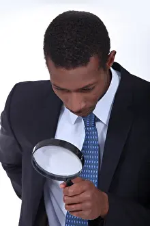 Examine Prints: Curious man inspecting an object with a magnifying glass