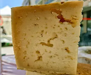 Handcrafted Prints: A cut piece of homemade sheep's cheese rests in the sun at a farmers' market in Spain