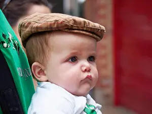 Street Scenes Prints: A cute baby boy with chubby cheeks wearing a flat tweed cap