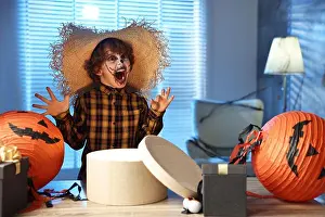 Preschooler Prints: Cute boy dressed like scarecrow with festive decor and gift boxes indoors at night