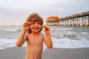 Little Boy Prints: Cute, happy child holding shell at the beach