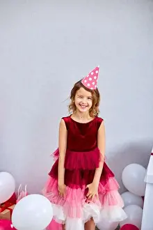 Balloons Prints: Cute, Joyful little girl in pink dress and hat play with balloons at home birthday party streamers