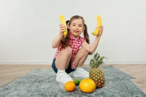 cute kid girl holding bananas in hand, playing with fruits