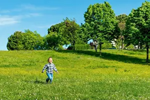 Infant Prints: Cute little boy running across grass und smiling outdoors in a public park garden