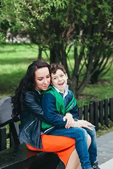 Cute little boy sit son his mother's lap in the park. A mother's love and tenderness