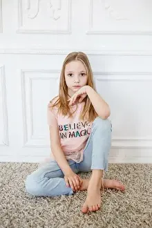 Cute pre-teen girl wearing fashion clothes posing in white interior. little but very serious girl