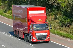 Delivering Prints: DAF CF Motorway. Red articulated trailer driving on UK motorway advertising its16 billions items delivered every year