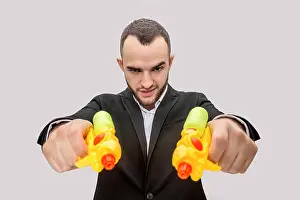 Revenge Prints: Dangerous young man in suit hold two water pistols in hands and direct them straight