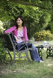 Weekends Prints: A dark haired woman sitting on a garden bench smiling