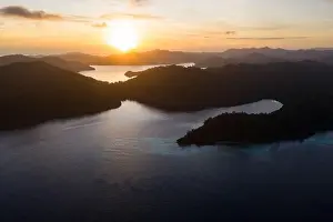 Dawn illuminates remote islands and the surrounding calm waters in Raja Ampat, Indonesia. This region is the epicenter of marine biodiversity