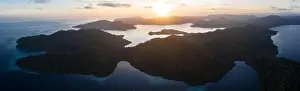 Dawn illuminates remote islands and the surrounding calm waters in Raja Ampat, Indonesia. This region is the epicenter of marine biodiversity