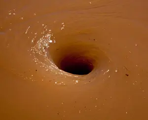 Vortex Prints: Deep brown flood water in river swirling into a whirlpool