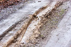 Dirt Road Prints: Deep tire tracks in wet mud on a gravel country road