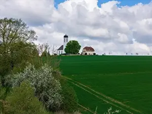 defaultSmall church with cemetery in the middle of blooming fruit trees and fields captured with a drone in spring