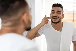 Dentistry Prints: Dental Health. Handsome Arab Man Looking In Mirror At His White Teeth