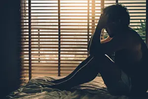 Trouble Prints: depressed man sitting head in hands on the bed in the dark bedroom with low light environment