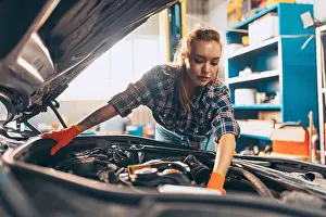 Screwdriver Prints: Destroying gender stereotypes. Young woman auto mechanic working at auto service station using different work tools