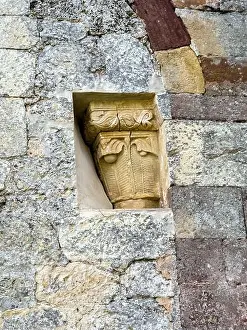Sculpted Prints: Detailed carved stone capital with decorative motifs on old church wall
