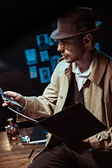 Professional Occupation Prints: Detective in trench coat and hat holding dossier and looking at photo