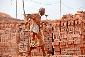 Air Pollution Prints: Dhaka, Bangladesh - April 30, 2023: Bangladeshi worker carries bricks in a brickfield at Savar in Dhaka