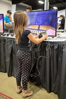 Diaper Prints: Still in diapers, a little girl tries computer gaming at a high tech exhibition in Costa Mesa