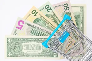 Different us dollar banknotes and empty shopping trolley. Flat lay photography