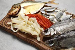 Salted Prints: Many different dried fish snacks on light grey table, closeup