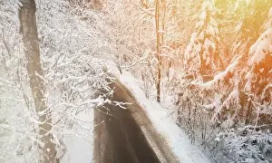 Dirty road in white winter snowy forest aerial drone view
