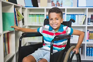 Disability Prints: Disabled boy selecting a book from bookshelf in library