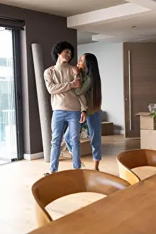 Relocation Prints: Diverse couple standing and smiling in modern living area