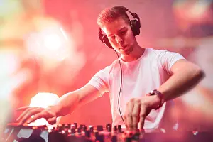 Mixing Prints: Dj mixing at party festival with red light and smoke in background - Summer nightlife view of disco club inside