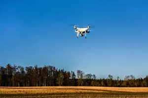 Spying Prints: DJI Phantom 4 PRO quadcopter drone in the air flying over a field, Germany