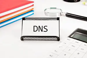 Domain Prints: DNS (Domain Name System) acronym. DNS on a business card in a stand on a white background