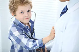Pediatrician Prints: Doctor and child patient. Little boy play with stethoscope while physician communicate with him