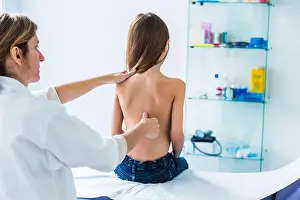 Doctor examining back of 7 year old girl
