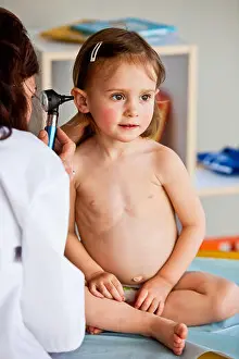 Pediatrician Prints: Doctor examining the ears of a 3-year-old girl with an otoscope