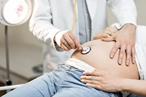 Gynecology Prints: Doctor listening to a pregnant woman's belly with a stethoscope during a medical examination