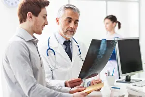 Professional Occupation Prints: Doctor in the office examining an x-ray and discussing with a patient